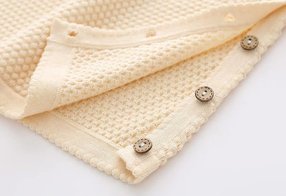 Close up of beige sweater top buttons