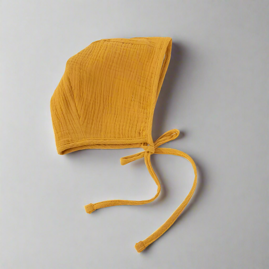 Mustard colored muslin bonnet laying flat