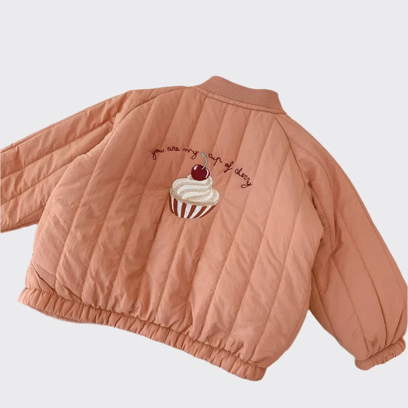 Pink bomber jacket with a cherry on top of a cupcake saying "you are my cup of cherry" embroidered close up