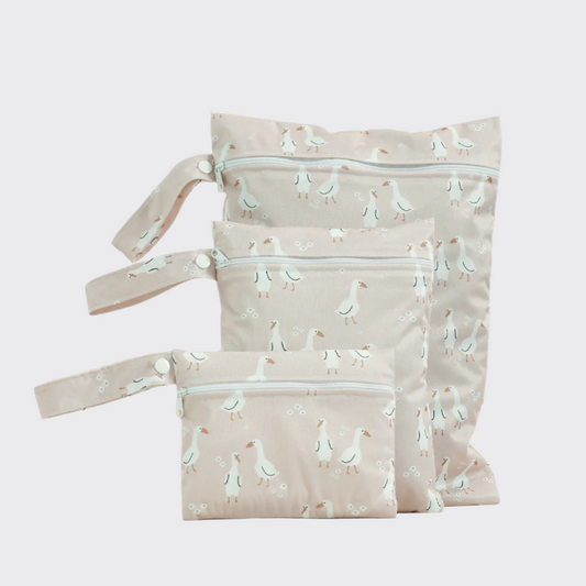 Wet diaper bag in beige patterned with white ducks, showing all three sizes